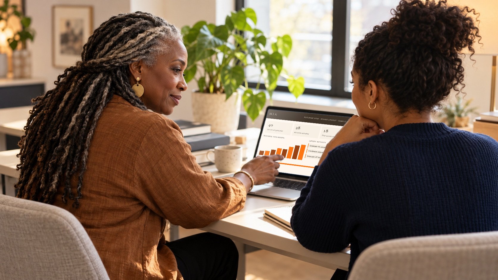 A program leader and a doula review a sample MIA program dashboard together on a laptop.